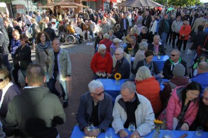 An verschiedenen Tischen sitzen Besucher und genießen ihr Glas Wein. Der Platz ist gut besucht.